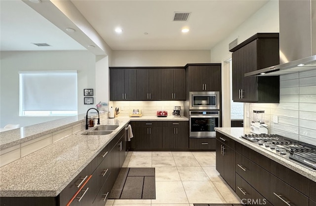 kitchen featuring backsplash, dark brown cabinets, sink, stainless steel appliances, and wall chimney exhaust hood