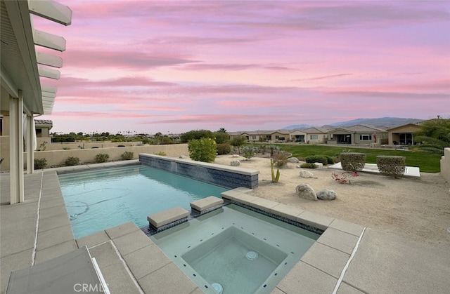 pool at dusk featuring an in ground hot tub