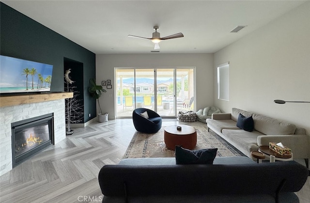 living room with a brick fireplace, light parquet floors, and ceiling fan