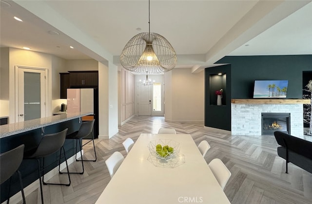 dining space with a chandelier, a fireplace, and light parquet flooring