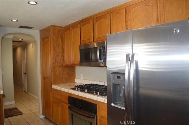 kitchen with light tile patterned floors, stainless steel appliances, and tile counters