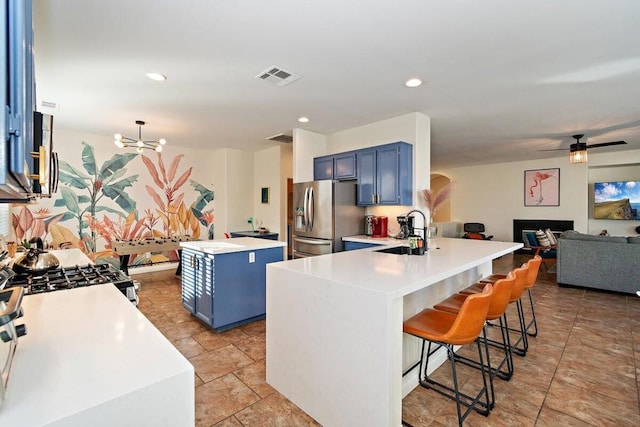 kitchen featuring stainless steel fridge with ice dispenser, kitchen peninsula, a breakfast bar area, blue cabinets, and pendant lighting