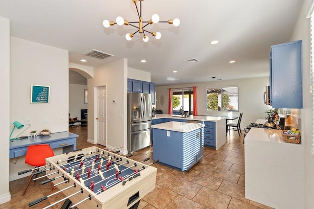 kitchen featuring kitchen peninsula, sink, an inviting chandelier, hanging light fixtures, and stainless steel fridge