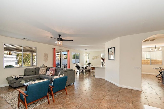 living room featuring light tile patterned floors, ceiling fan with notable chandelier, and plenty of natural light