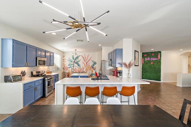 kitchen featuring a kitchen bar, stainless steel appliances, a notable chandelier, tile patterned flooring, and blue cabinets