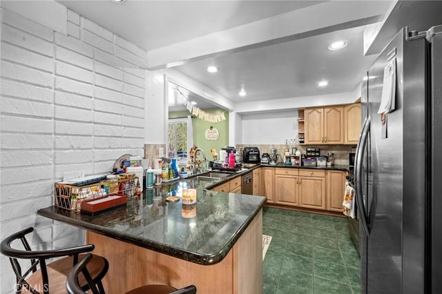 kitchen with kitchen peninsula, appliances with stainless steel finishes, backsplash, dark stone counters, and sink