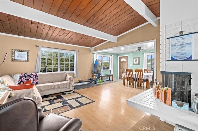 living room featuring a fireplace, vaulted ceiling with beams, light hardwood / wood-style flooring, and a wealth of natural light