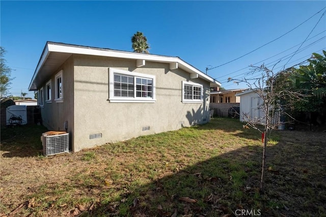 view of side of property with a storage unit, a lawn, and central air condition unit