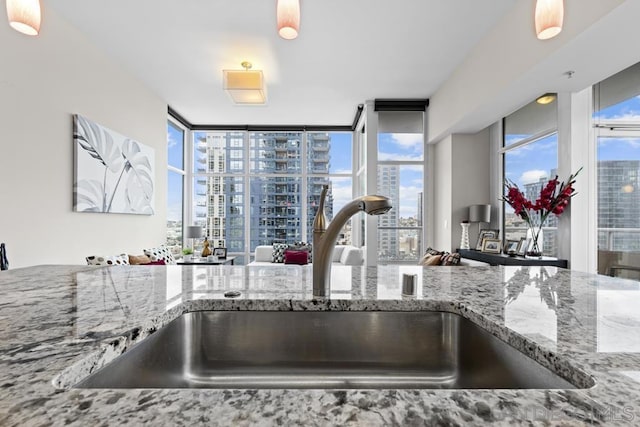 kitchen with sink, light stone counters, and floor to ceiling windows