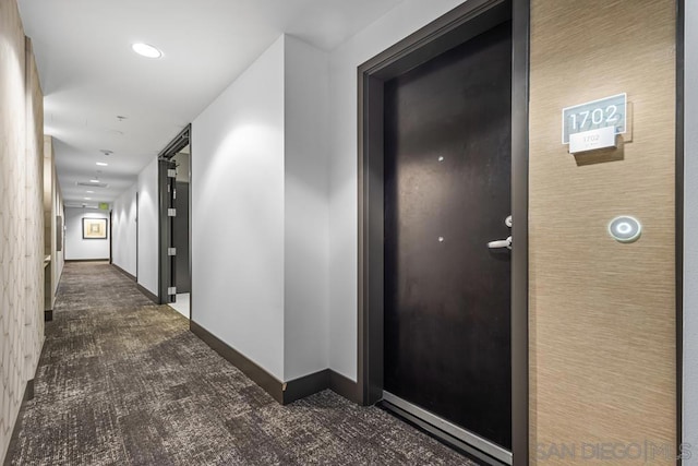 corridor featuring dark colored carpet