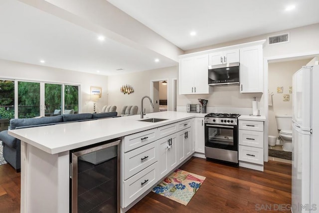 kitchen with sink, kitchen peninsula, stainless steel appliances, beverage cooler, and white cabinets