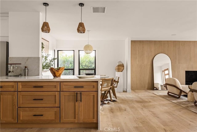 kitchen featuring hanging light fixtures, light wood-type flooring, and a fireplace