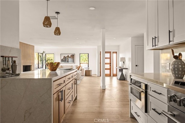 kitchen featuring pendant lighting, white cabinetry, appliances with stainless steel finishes, and light hardwood / wood-style flooring