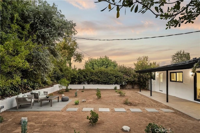 yard at dusk featuring an outdoor living space and a patio area