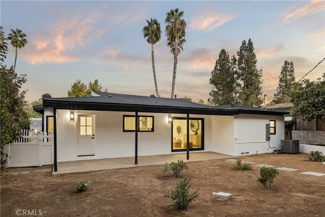 back house at dusk featuring central AC unit and a patio