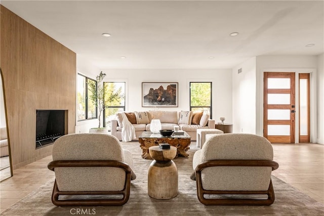 living room featuring a large fireplace, light hardwood / wood-style flooring, and plenty of natural light