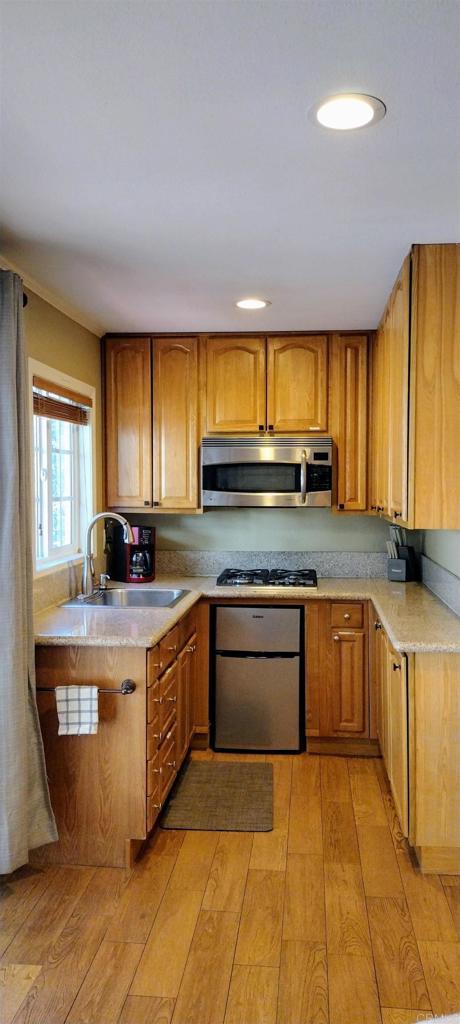 kitchen with sink, stainless steel appliances, and light hardwood / wood-style floors