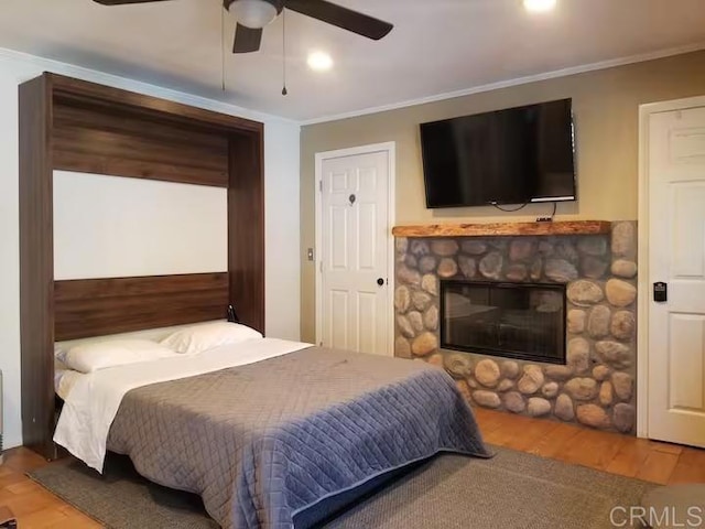 bedroom featuring ceiling fan, a fireplace, ornamental molding, and hardwood / wood-style flooring