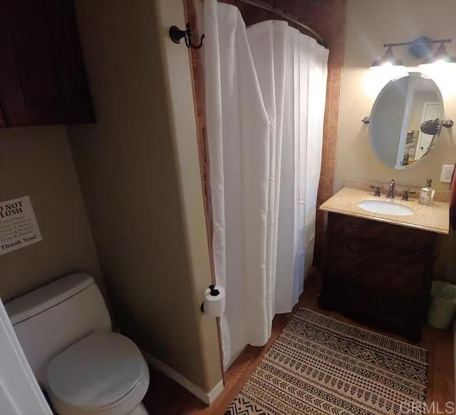 bathroom featuring toilet, vanity, and hardwood / wood-style flooring