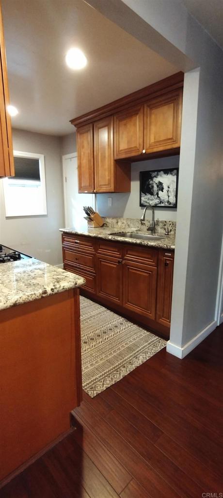 kitchen with light stone countertops, sink, dark hardwood / wood-style floors, and gas cooktop