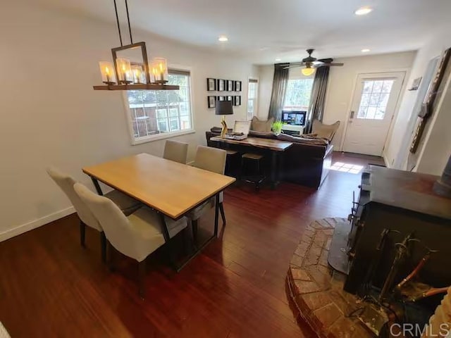 dining space featuring ceiling fan with notable chandelier and dark hardwood / wood-style flooring