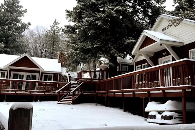 snow covered back of property with a deck