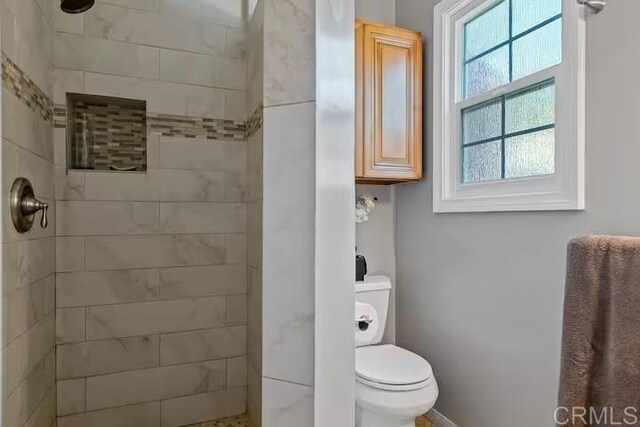 bathroom with tiled shower and toilet