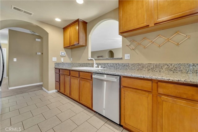 kitchen featuring light stone counters, sink, dishwasher, and light tile patterned flooring