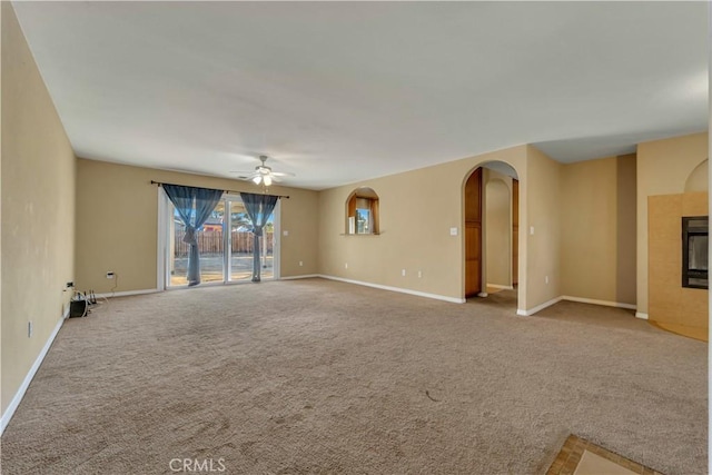 unfurnished living room featuring ceiling fan, a tiled fireplace, and carpet floors