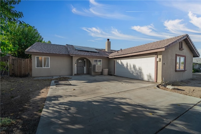 ranch-style house with a garage and solar panels