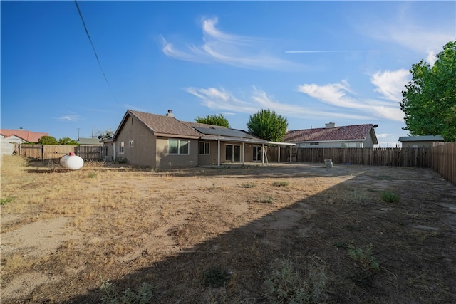 back of house featuring solar panels