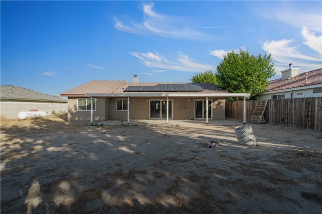 back of property with a patio area and solar panels