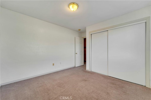 unfurnished bedroom featuring a closet and light carpet