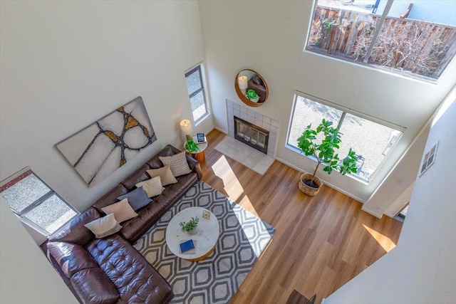 living room featuring light hardwood / wood-style floors, a towering ceiling, and a tile fireplace