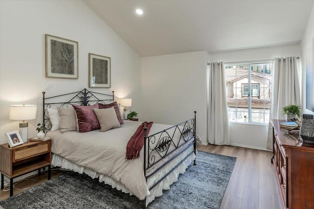 bedroom with vaulted ceiling and light hardwood / wood-style flooring