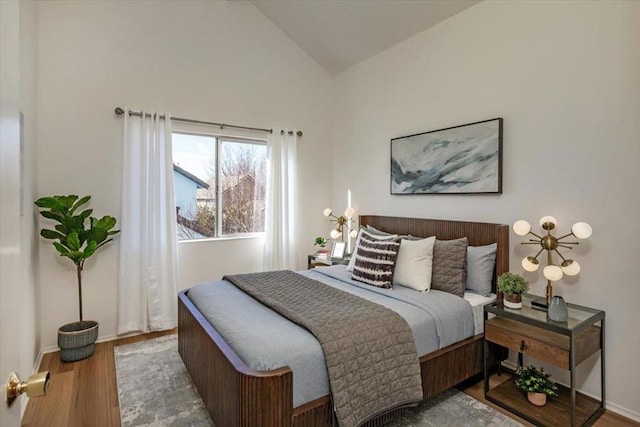 bedroom with high vaulted ceiling and wood-type flooring