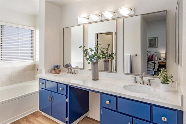 bathroom featuring vanity, a tub, and wood-type flooring