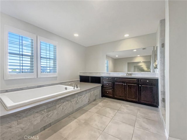 bathroom with a relaxing tiled tub, tile patterned floors, and vanity