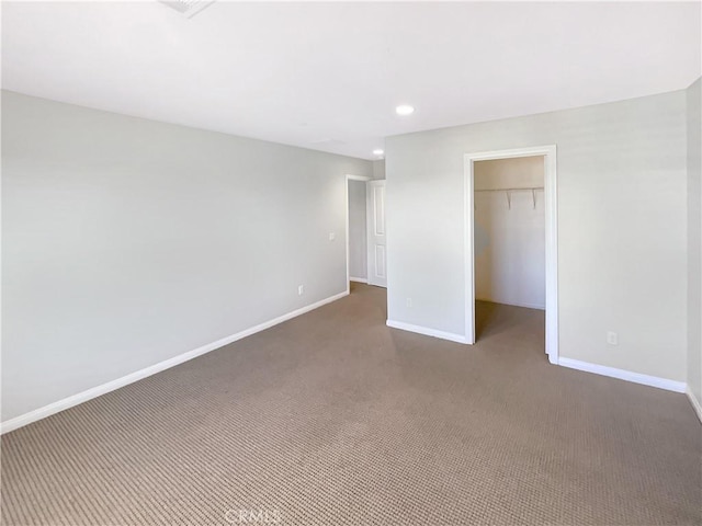 unfurnished bedroom featuring a spacious closet, dark carpet, and a closet