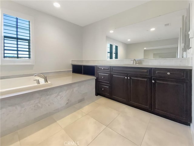 bathroom featuring vanity, a wealth of natural light, tile patterned floors, and tiled bath