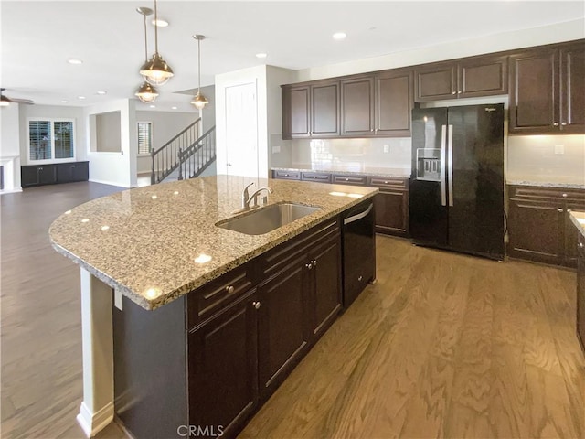 kitchen featuring sink, dark brown cabinetry, black appliances, an island with sink, and decorative light fixtures