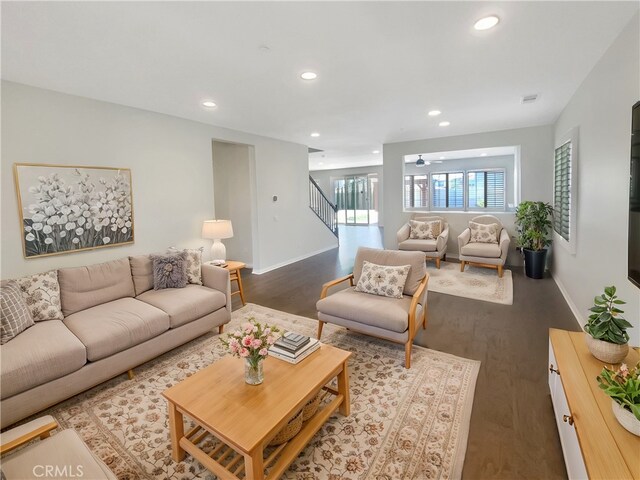 living room featuring ceiling fan and dark wood-type flooring