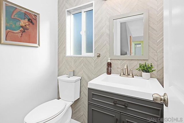 bathroom featuring vanity, tile walls, and toilet