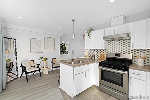 kitchen with sink, gas stove, kitchen peninsula, pendant lighting, and white cabinets