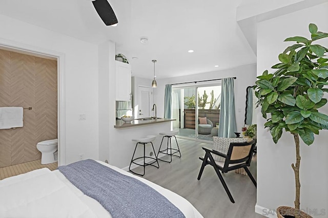 bedroom with sink, light hardwood / wood-style flooring, stainless steel refrigerator, ceiling fan, and access to outside