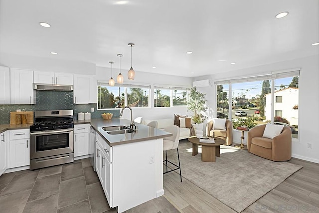 kitchen with pendant lighting, sink, a breakfast bar, appliances with stainless steel finishes, and white cabinetry