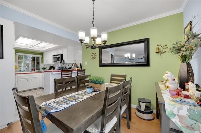 dining room with light wood-type flooring, crown molding, and a notable chandelier