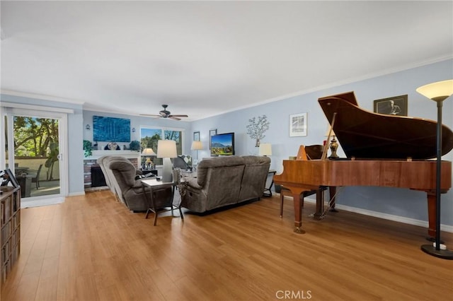 living room featuring light wood-type flooring, ceiling fan, a wealth of natural light, and crown molding