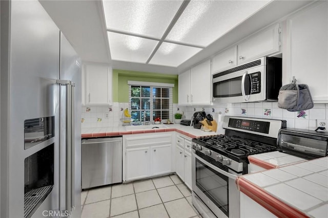 kitchen with sink, white cabinets, stainless steel appliances, and tile countertops