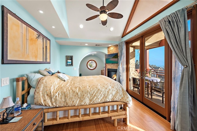 bedroom with lofted ceiling, a fireplace, light hardwood / wood-style floors, and access to outside